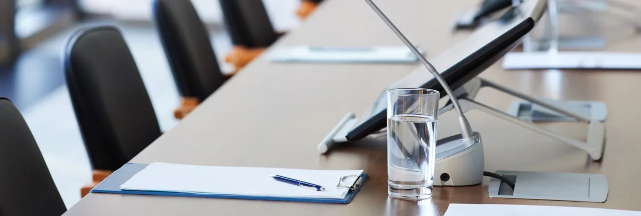 Konferenzraum mit Besprechungstisch, Unterlagen und Mikrofonen. Professionelle Arbeitsatmosphäre bei HB partners